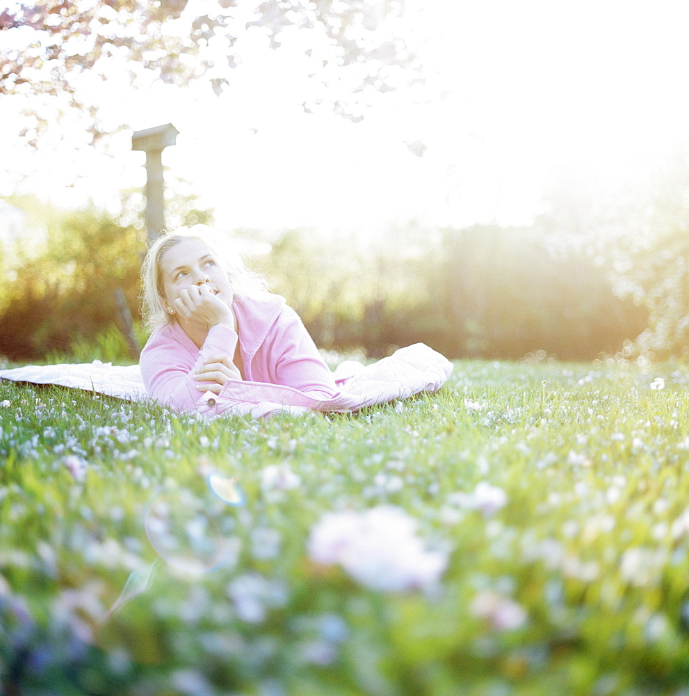 Woman relaxing on lawn surrounded by cherry blossom, Washington State, USA