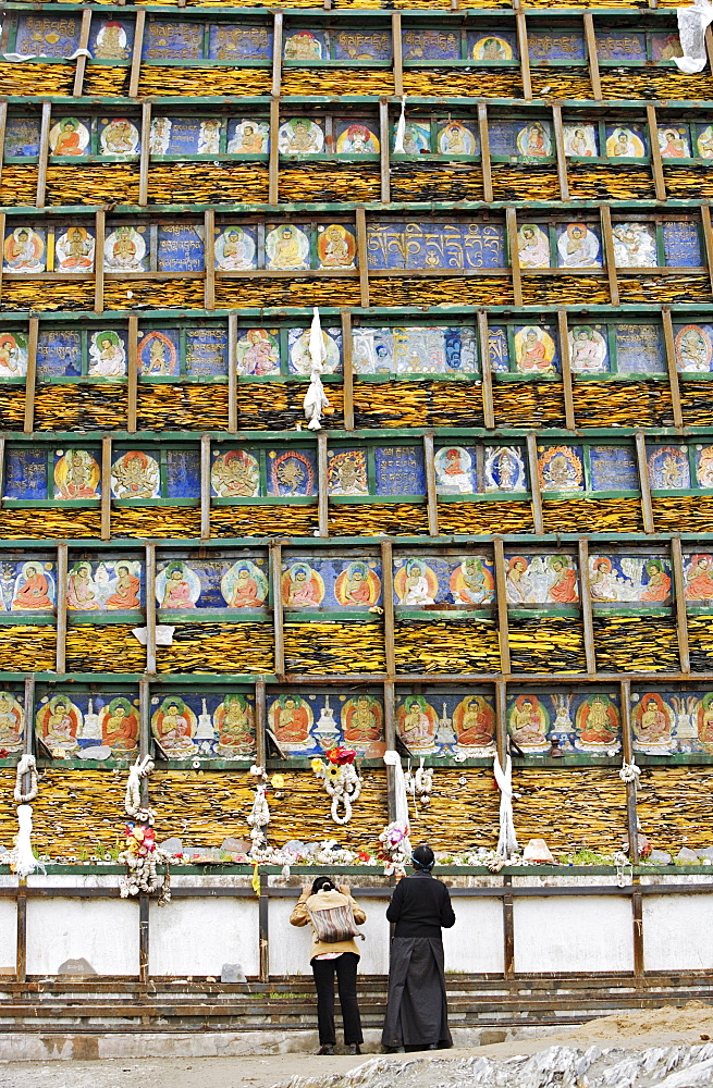 Two women stop at a Buddhist shrine on the Lingkhor Lam, a traditional pilgrimage circuit around the city of Lhasa, Tibet, China, Asia