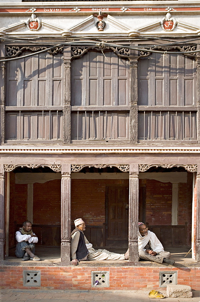 Three old men watch the world go by on a street in Bhaktapur, Kathmandu valley, Nepal, Asia