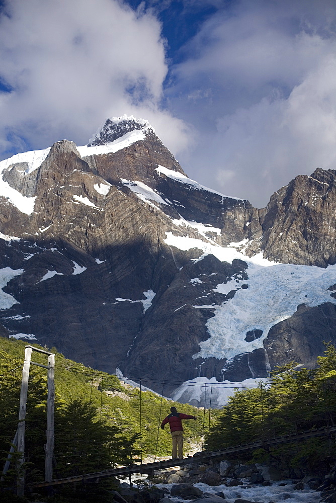 Woman standing on a suspension bridge over glacial fed river, Torres Del Paine National Park, Chile, South America