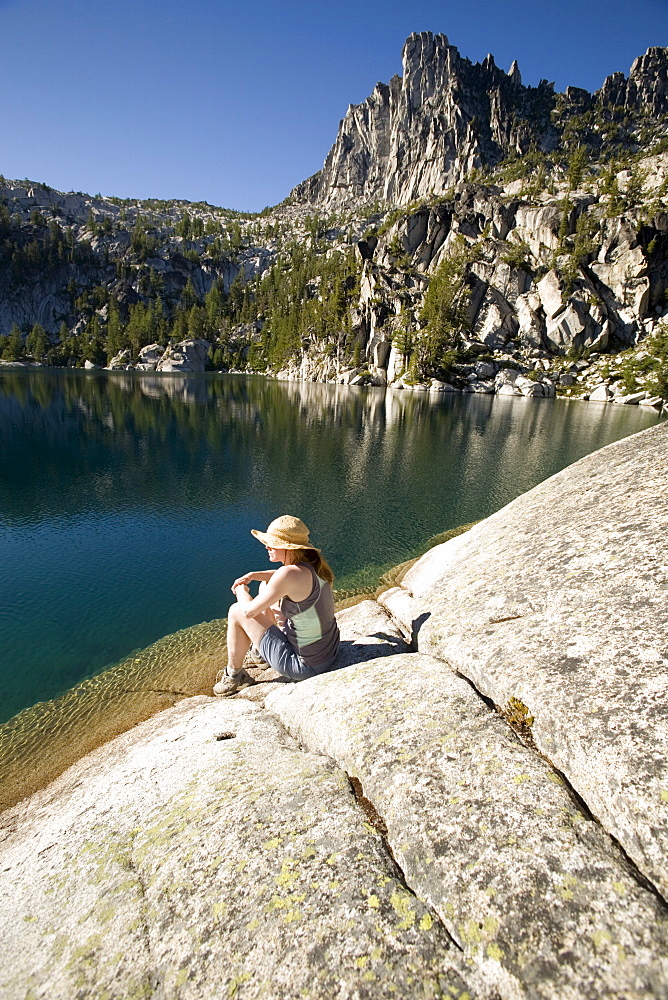 Woman sitting on the shore of Lake Viviane, Prusik Peak, Enchantment lakes, Alpine Lakes Wilderness, Levenworth, Washington State, United States of America, North America