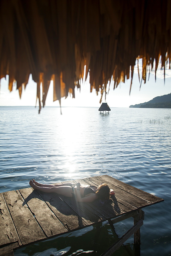 Woman relaxing on dock, El Remate, Lago Peten Itza, Guatemala, Central America