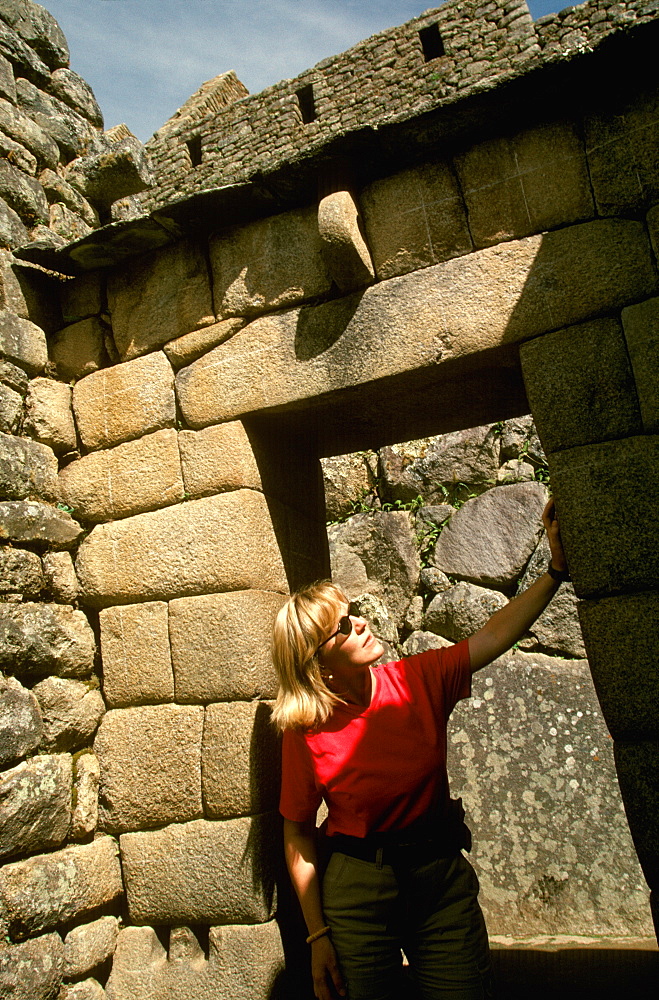 Machu Picchu a visitor examines the finely cut stones that form the entrance to the precinct of the Temple of the Sun, Highlands, Peru