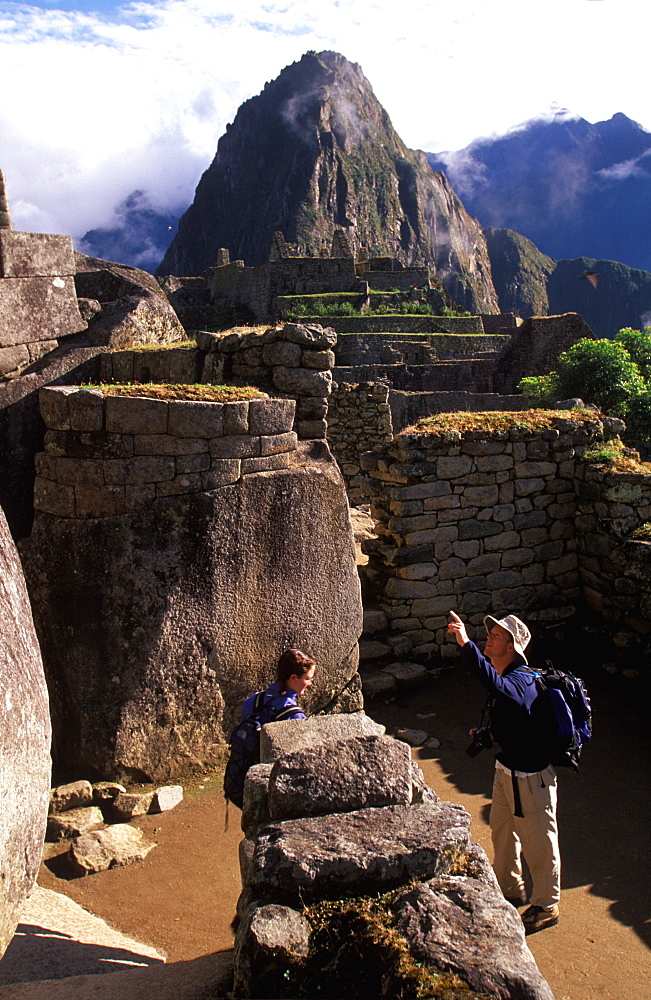 Machu Picchu the Temple of the Sun with the site's most perfect stonework visitors view grotto called the Royal Tomb below the temple, Highlands, Peru