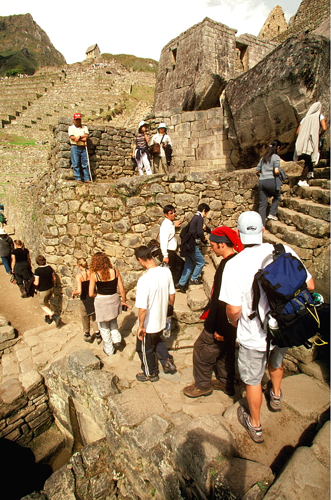 Machu Picchu visitors on steps next to the fountains which are actually sixteen small waterfalls in a series of baths used ritually, Highlands, Peru