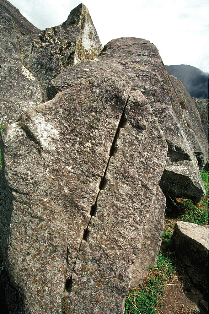 Machu Picchu a stone in the quarry area shows how stone was cut with primitive tools using wood wedges that expand with water, Highlands, Peru