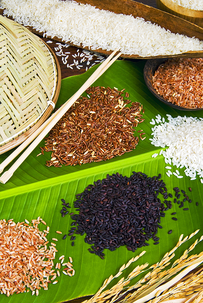 Various types of rice: black, arborio, basmati, red, parboiled on a banana leaf