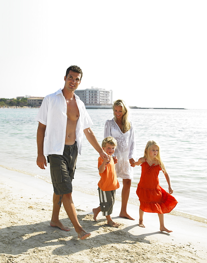 Parents and children (6-8) walking on beach