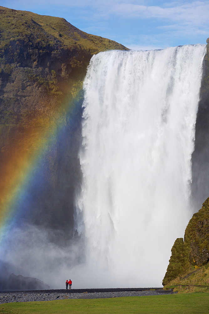 Tourists in red jacket at 62 m high Skogafoss waterfall, Skogar, South area, Iceland, Polar Regions