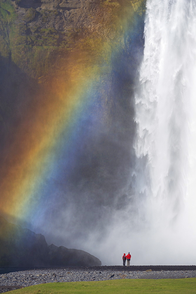 Tourists in red jacket at 62 m high Skogafoss waterfall, Skogar, South area, Iceland, Polar Regions