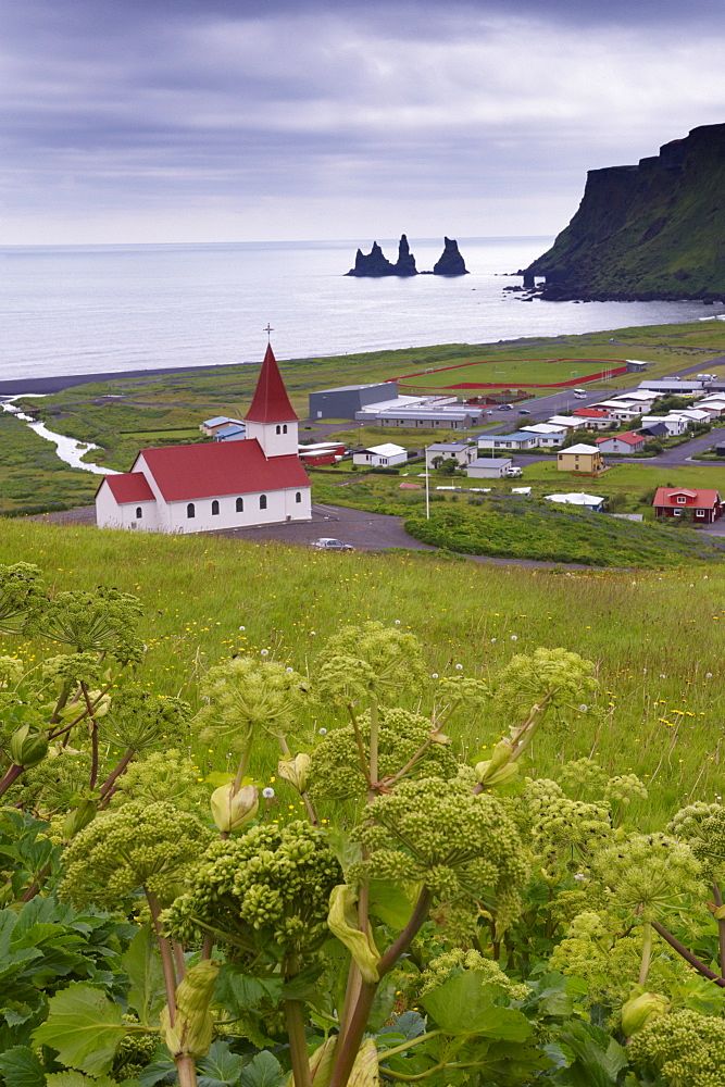 Church and village of Vik (Vik a Myrdal) and Reynisdrangar sea stacks in the distance, south coast of Iceland (Sudurland), Iceland, Polar Regions