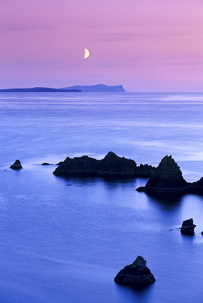 Sunset over Sand Wick and rising moon over Foula in distance, Eshaness, Shetland, Scotland, United Kingdom, Europe