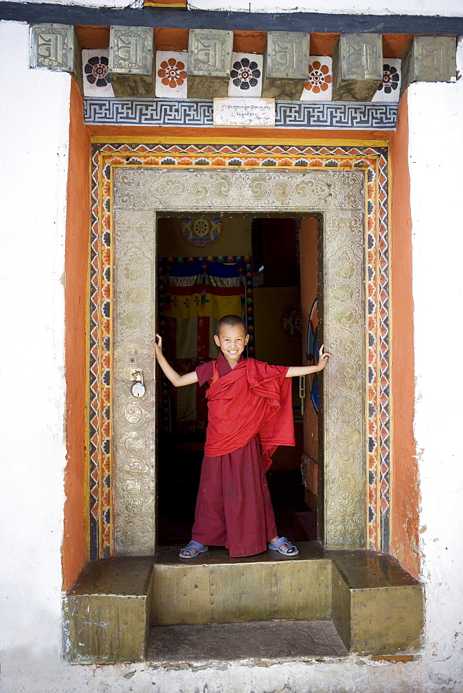 Young Buddhist monk in doorway, Paro Dzong, Paro, Bhutan, Asia