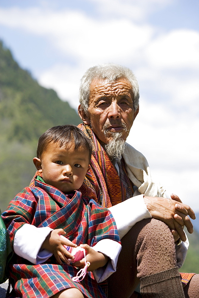 Old man and little boy at Buddhist festival (Tsechu), Haa Valley, Bhutan, Asia