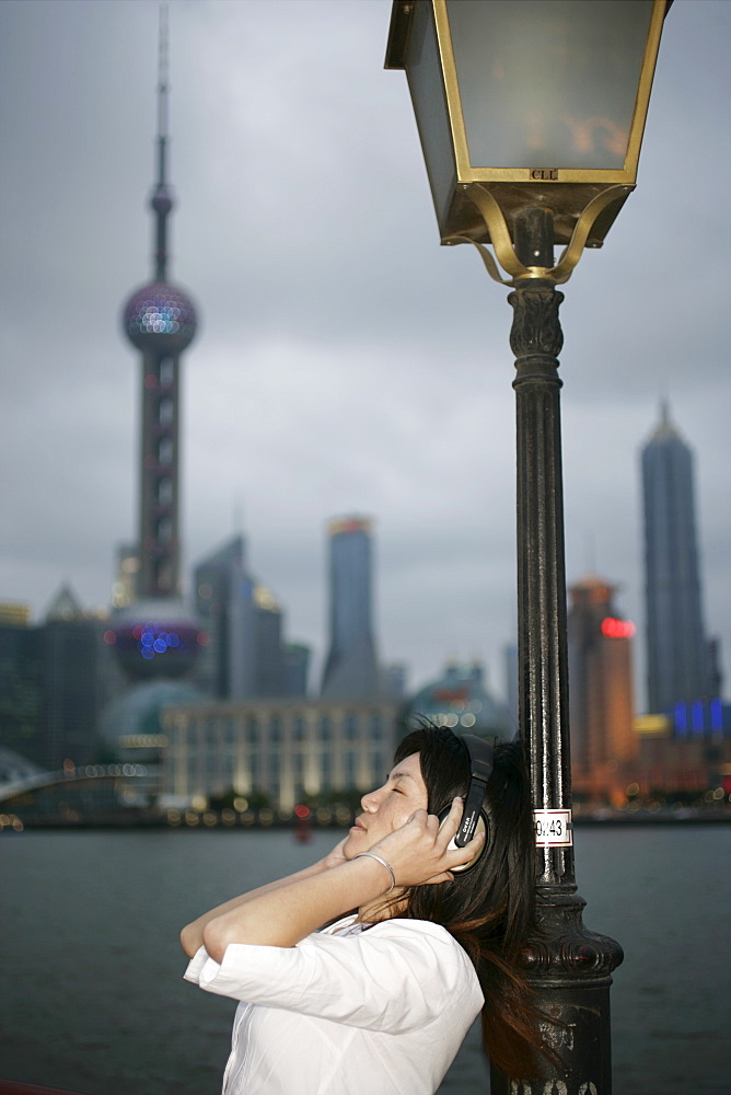 Chinese woman listening to music, the Bund, Shanghai, China, Asia