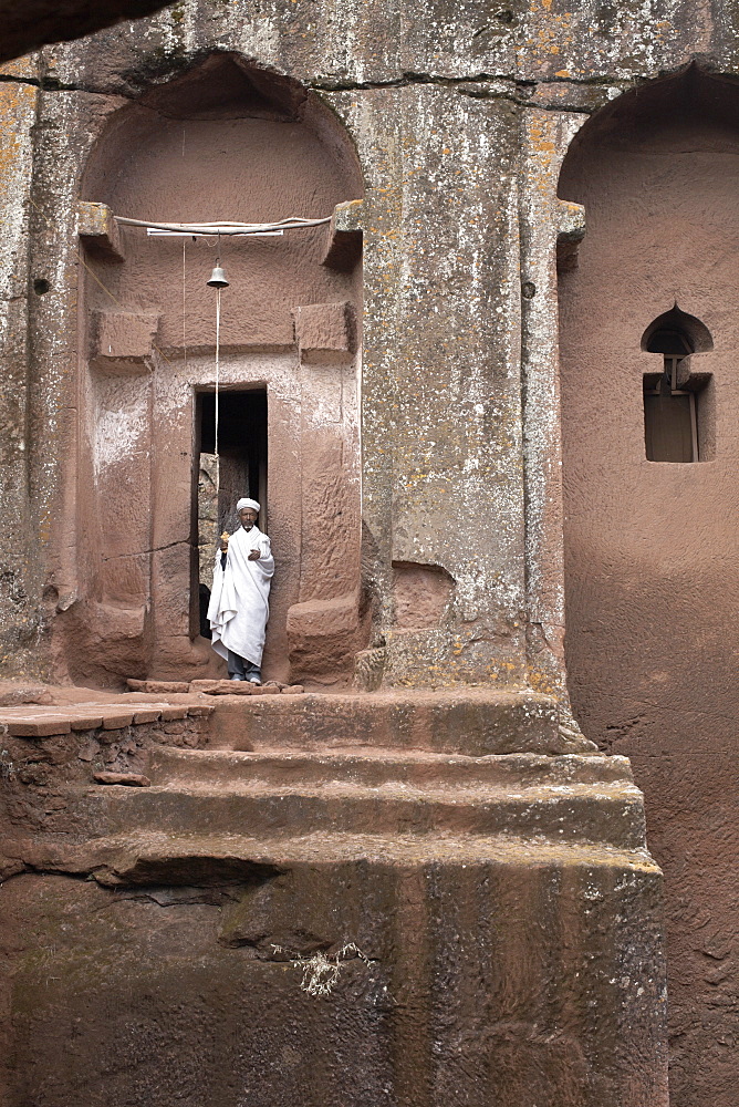 A priest stands at the entrance to the rock-hewn church of Bet Gabriel-Rufael, in Lalibela, UNESCO World Heritage Site, Ethiopia, Africa