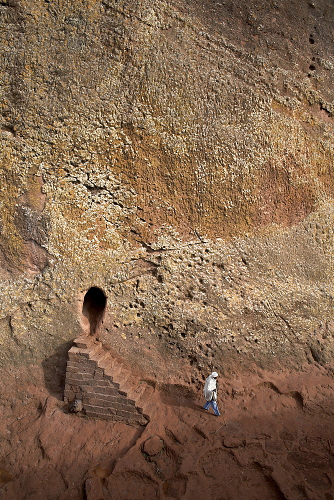 A woman emerges from a tunnel leading to the rock-hewn church of Bet Amanuel, in Lalibela, Ethiopia, Africa