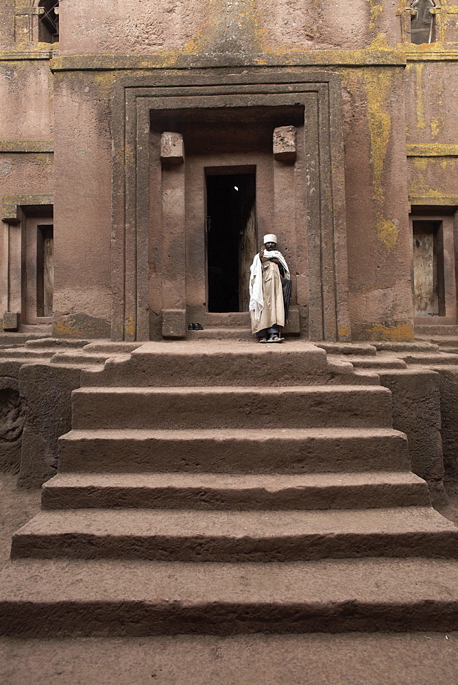 A priest stands at the entrance to the rock-hewn church of Bet Giyorgis (St. George), in Lalibela, UNESCO World Heritage Site, Ethiopia, Africa