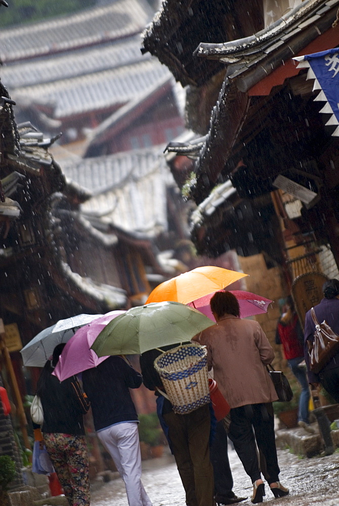 Locals with umbrellas in rain, Lijiang old town, UNESCO World Heritage Site, Yunnan, China, Asia