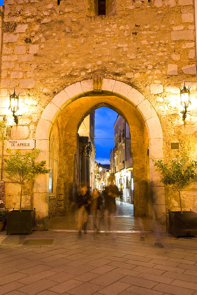 People strolling in the evening, Piazza IX Aprile, gateway through Torre dell Orologio, Taormina, Sicily, Italy, Europe