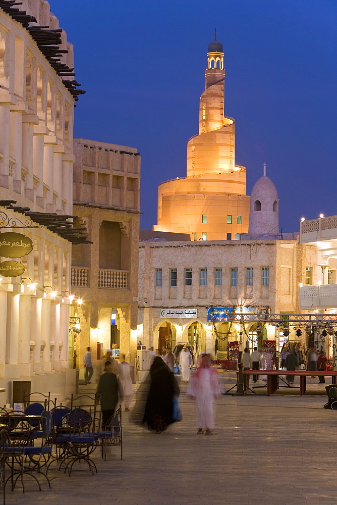 The restored Souq Waqif looking towards the illuminated spiral mosque of the Kassem Darwish Fakhroo Islamic Centre based on the Great Mosque in Samarra in Iraq, Doha, Qatar, Middle East