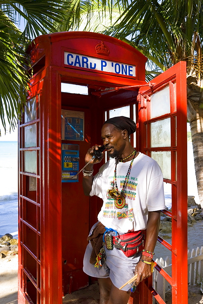 Traditional English red telephone box on the beach at Dickenson Bay, Antigua, Leeward Islands, West Indies, Caribbean, Central America