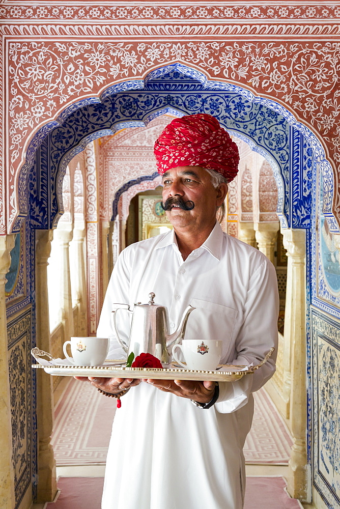 Waiter carrying tea tray in ornate passageway, Samode Palace, Jaipur, Rajasthan, India, Asia