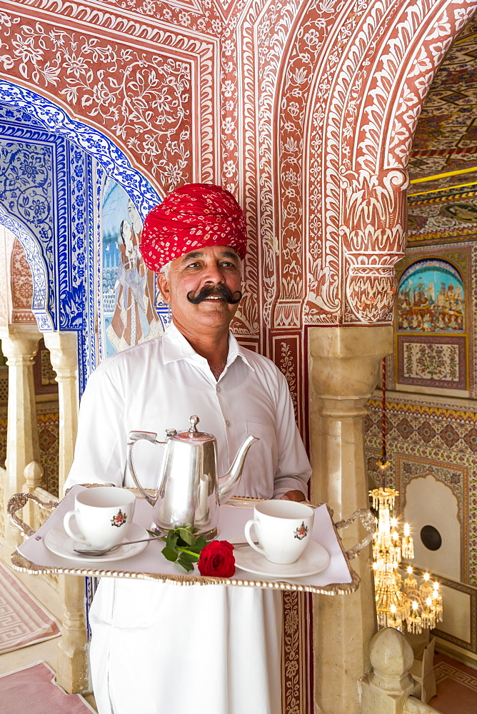 Waiter carrying tea tray in ornate passageway, Samode Palace, Jaipur, Rajasthan, India, Asia