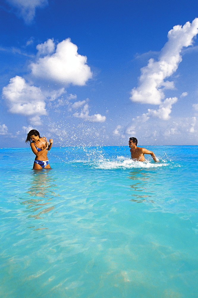 Couple splashing in the sea, Maldives, Indian Ocean, Asia