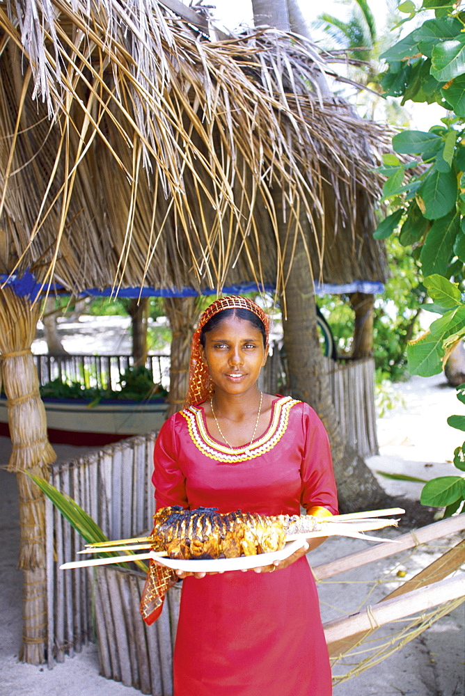 Maldivian woman offering a plate of grilled fish, Maldives, Indian Ocean, Asia