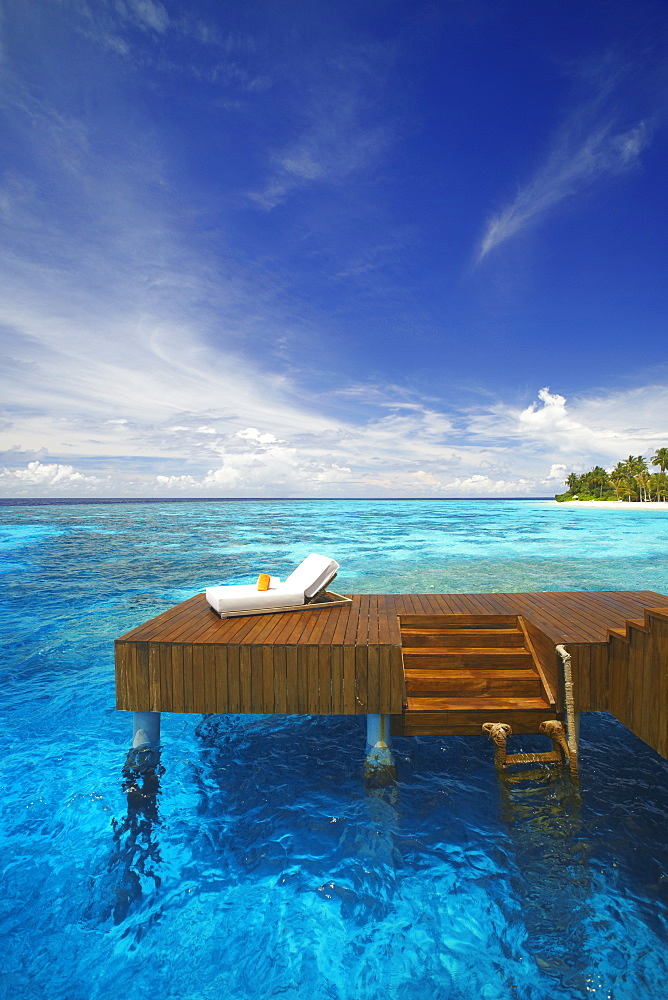 Sun lounger and jetty in blue lagoon on tropical island, Maldives, Indian Ocean, Asia