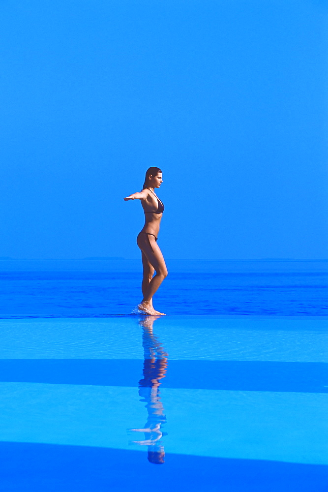 Woman walking at the Edge of Infinity pool, Maldives, Indian Ocean, Asia