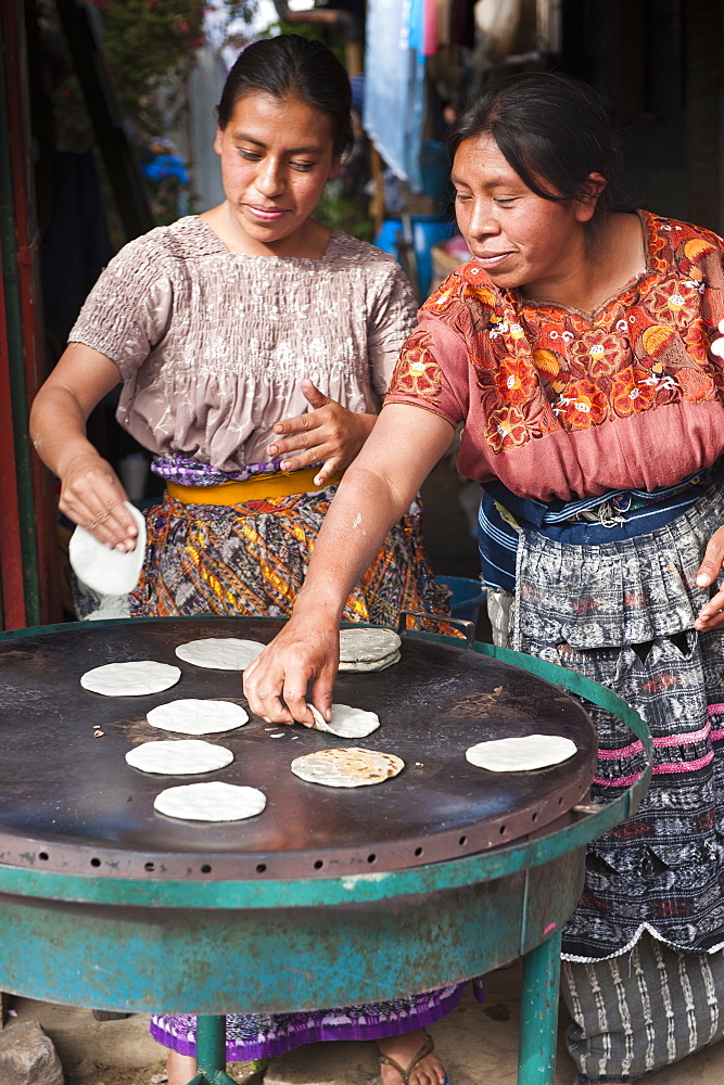 Mayan women baking tortillas in the market at Santiago Sacatepequez, Guatemala, Central America