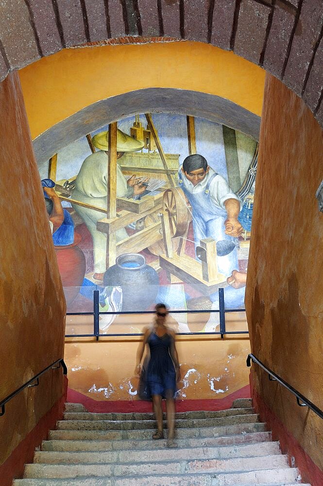 Mexico, Bajio, San Miguel de Allende, Bellas Artes Mural by Pedro Martinez dated 1940 with woman descending flight of stairs in foreground.