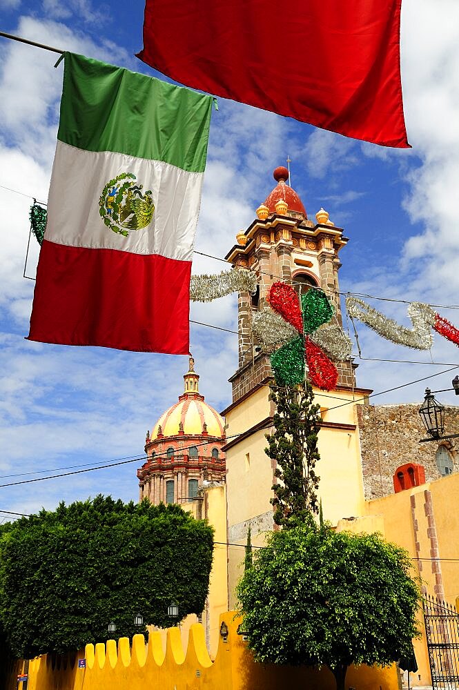 Mexico, Bajio, San Miguel de Allende, Mexican flags and Independence Day decorations hang in foreground of church.