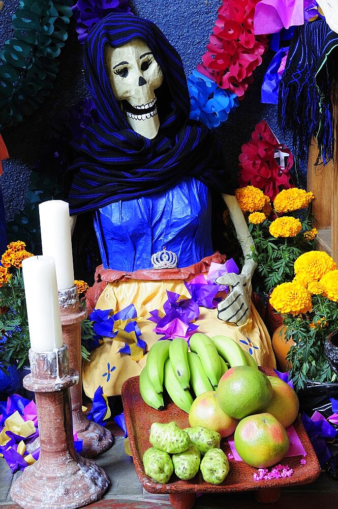 Mexico, Michoacan, Patzcuaro, Dia de los Muertos Day of the Dead altar with figures food candles and flowers.