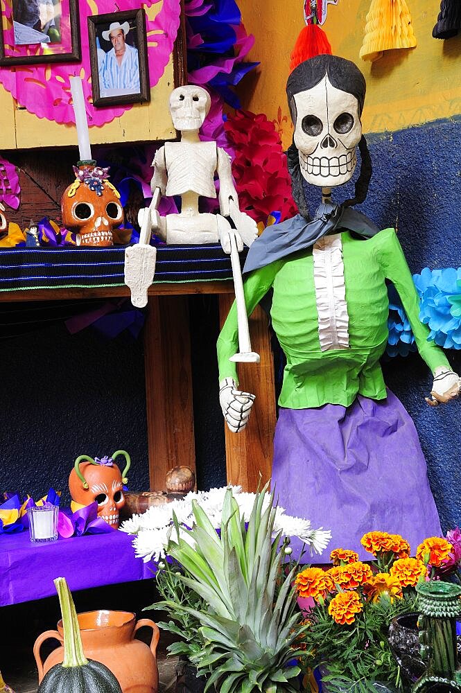 Mexico, Michoacan, Patzcuaro, Dia de los Muertos Day of the Dead altar with skeleton figures flowers and colourful paper decorations.