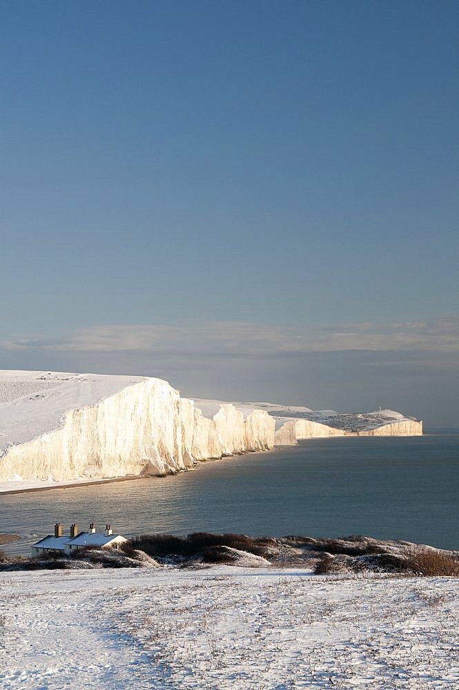 England, East Sussex, Seven Sisters, Snow covered coastline from Birling gap showing the Coastguard cottages in the foreground and Belle Tout lighthouse in the distance.