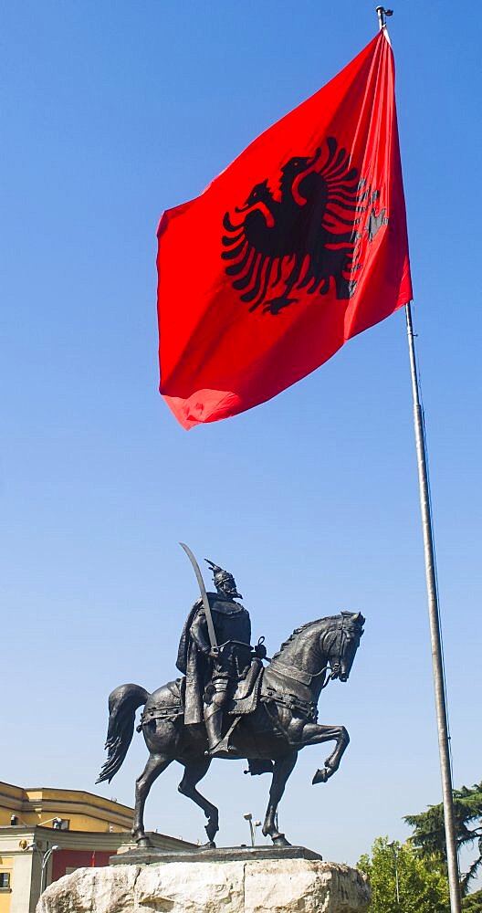 Albania, Tirana, Sculpture of National Hero Skanderbeg mounted on his horse with sword below the national flag.