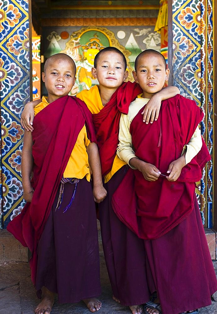 Bhutan, Punakha, Three young novice monks standing in doorway of Chimi Lakhang temple in the old capital.