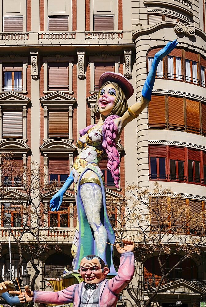 Spain, Valencia Province, Valencia, Papier Mache figure of a woman standing on another figures shoulders in the street during Las Fallas festival.