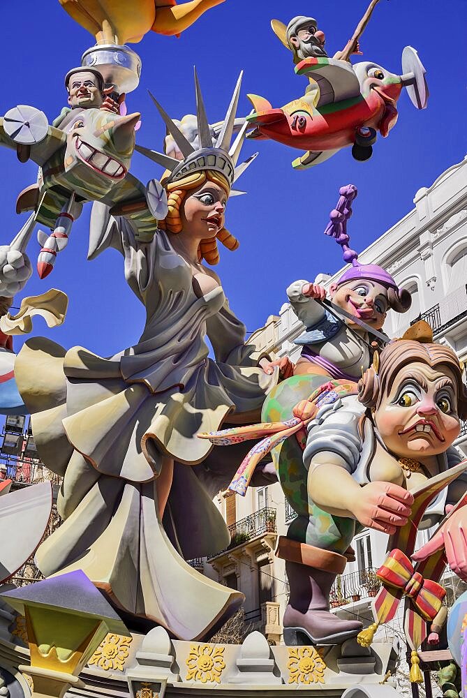 Spain, Valencia Province, Valencia, Papier Mache figure of a woman resembling the Statue of Liberty with various other figures flying around her during Las Fallas festival.