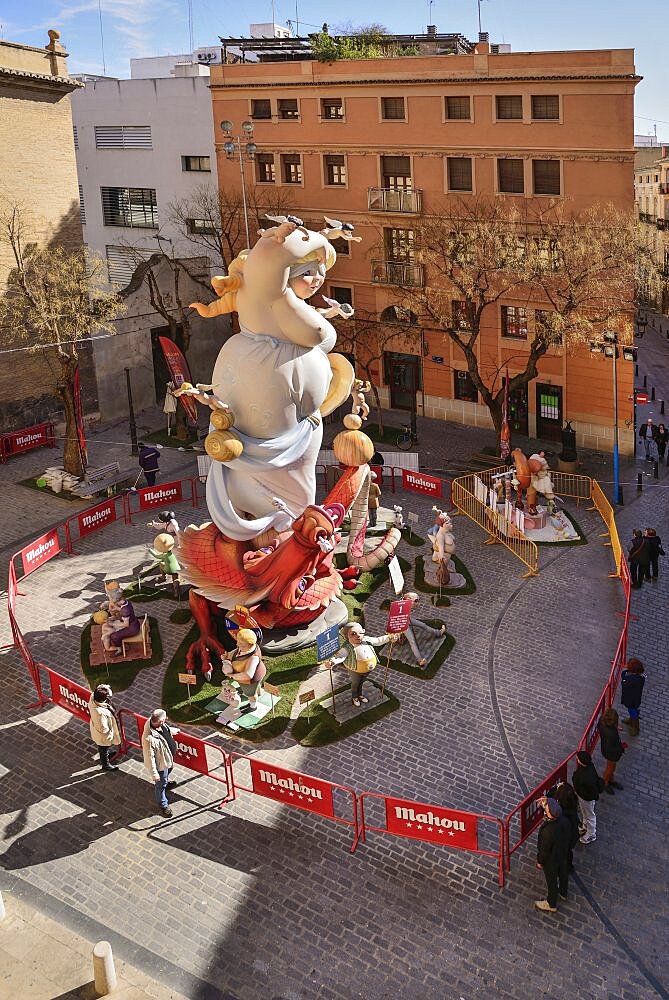 Spain, Valencia Province, Valencia, Papier Mache falla scene with onlookers viewing a giant figure of a lady in the street at Torres de Quart during Las Fallas festival.