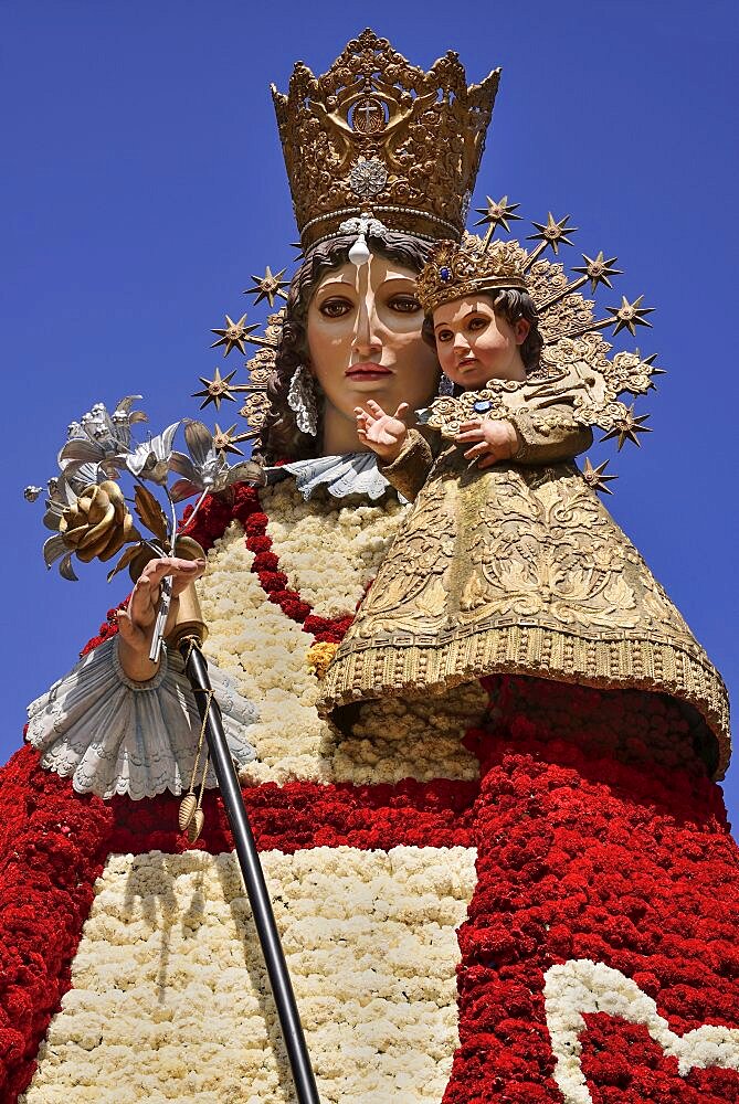 Spain, Valencia Province, Valencia, Statue of Virgen de los Desamparados, Our Lady of the Forsaken, decked out with flowers carried in the religious procession during Las Fallas festival.