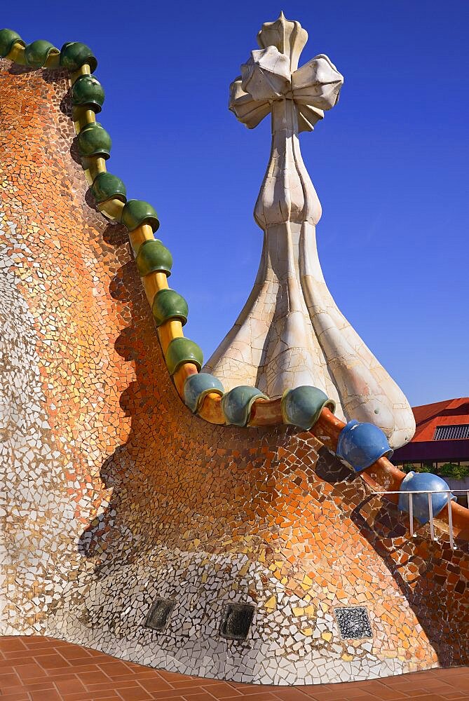 Spain, Catalunya, Barcelona, Antoni Gaudi's Casa Batllo building, dragon's back feature on the roof terrace with the four armed cross also inclluded.