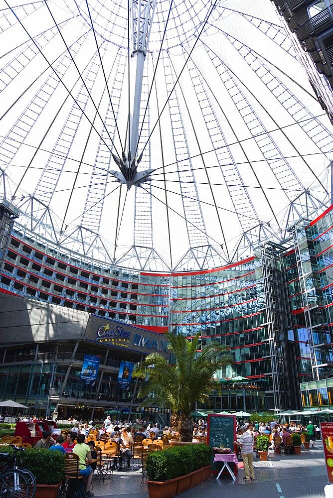 Germany, Berlin, Mitte, Potsdamer Platz, The Sony Centre designed by architect Helmut Jahn with the canopy over the central Forum of restaurants, offices, cinemas, shops and apartments with people eating at tables.