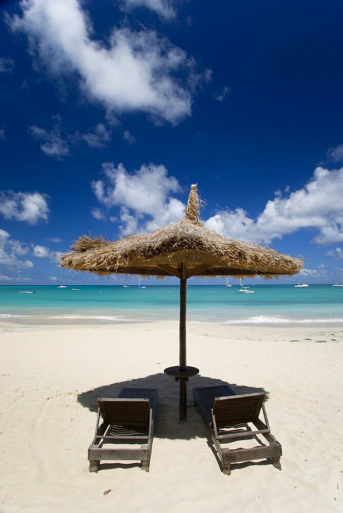 WEST INDIES St Vincent & The Grenadines Canouan Palapa thatched shelter and sunbeds at Tamarind Beach Hotel in Charles Bay with moored yachts