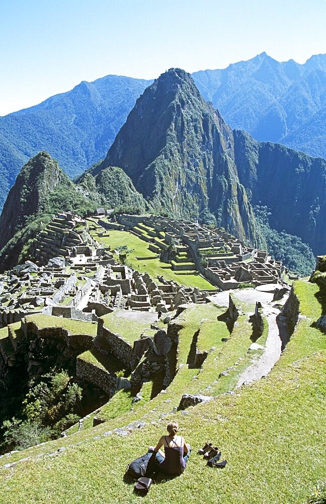 PERU Cusco Department Machu Picchu Inca ruins  terraces  visitor sitting on terrace  and Huayna Picchu. Cuzco Travel Tourism Holiday Vacation Explore Recreation Leisure Sightseeing Tourist Attraction Tour Destination Machu Picchu Machupicchu Huayna Wayna Peru Peruvian Culture Cultural Tranquil Tranquility Sacred Valley Of The Inca Incas Hill Hillside Trail Mountain Mountainous Mountainside Overlooking Overlook Scenic Landscape View Vista Picturesque Dominant Dominating Prominent Andes Andean Ruins Remains Ancient Civilisation Civilization Peak High Tall Range Altitude Architecture Architectural Archaeology Archaeological UNESCO Peaceful Landmark Vast Citadel Panorama Panoramic Spiritual Lost City Remote Spectacular Magnificent Beautiful Secluded Seclusion Isolated Terrace Terraces Woman Lady Person Sightseer Holidaymaker Alone Solitary Single One 1 Calendar American Cusco South America