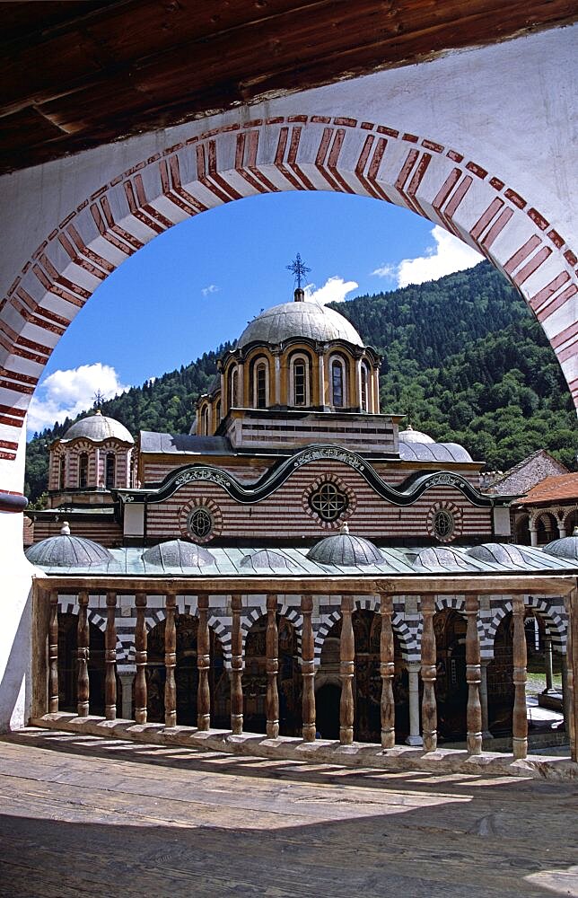 BULGARIA  Rila Nativity Church from balcony through arch  Rila Monastery. Travel Tourism Holiday Vacation Explore Recreation Leisure Sightseeing Tourist Attraction Tour History Historic Historical Nativity Church Religion Religious Building Architecture Architectural Tranquility Tranquil Calm Peaceful Christianity Orthodox Holy Divine Christian Theology Pray Prayer Worship Worshipping Worshiping Faith Bulgaria Bulgarian East Eastern Europe European Calendar Vivid Vibrant Rila Monastery Monastic Ornate Intricate UNESCO World Heritage Site Rilski Museum Summer Bright Sunny Sun Monument National Arches Arch Arched Balcony Blue Sky Stripes Stripe Striped Symmetry Symmetrical Graphic Banister Dome Frame Framed Framing Eastern Europe