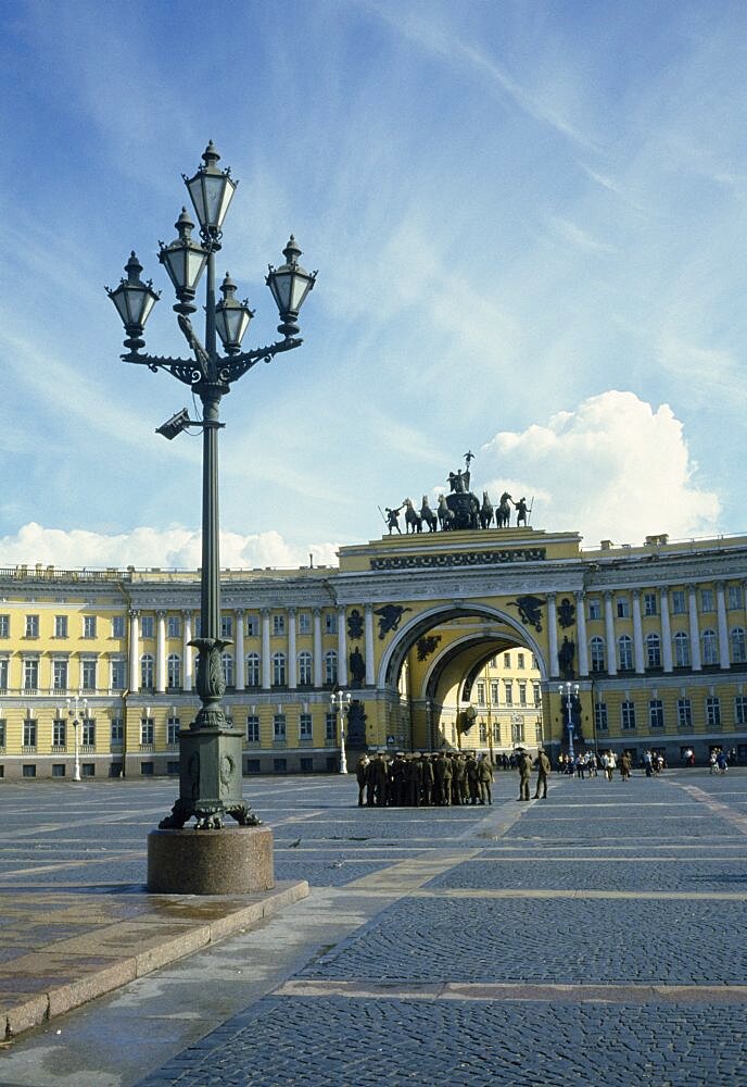 Winter Palace, Uniformed soldiers gathered in the courtyard with lampost in the foreground and archway behind, The Hermitage, St Petersburg, Russia